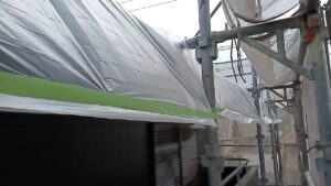 中津川市です。今晩、雨が降ります。
ベランダの床に這ったコンパネに雨が掛からないようにします。
軒樋から養生テープを足場に掛けます。